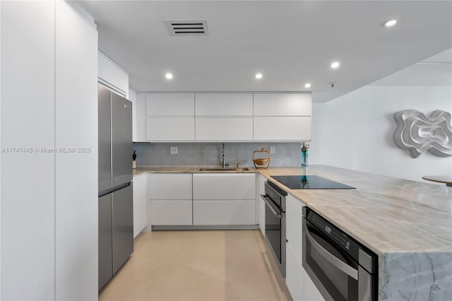 kitchen with modern cabinets, visible vents, black appliances, and a sink