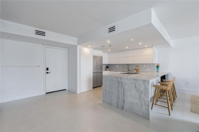 kitchen with white cabinets, modern cabinets, visible vents, and freestanding refrigerator