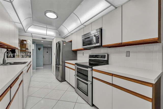 kitchen with white cabinetry, stainless steel appliances, light tile patterned floors, and sink