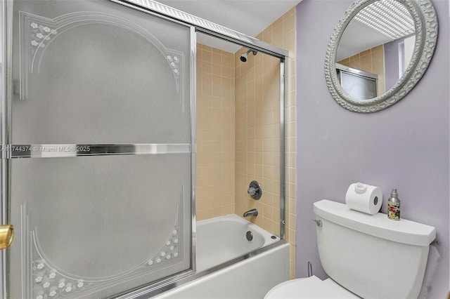 bathroom featuring bath / shower combo with glass door and toilet