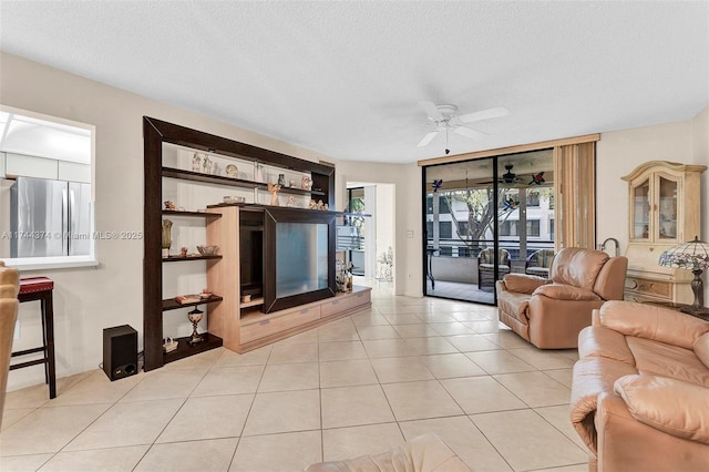 living room with ceiling fan, light tile patterned floors, and a textured ceiling