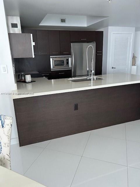 kitchen featuring appliances with stainless steel finishes, dark brown cabinets, and light tile patterned floors