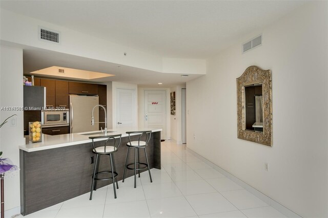 150 Sunny Isles Blvd Unit 1-606, Sunny Isles Beach, FL 33160 - kitchen featuring freestanding refrigerator, stainless steel microwave, a peninsula, a kitchen breakfast bar, and light countertops