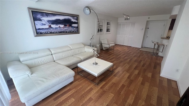 living room featuring a textured ceiling, wood finished floors, and baseboards