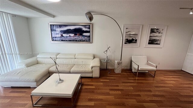 living area with baseboards, a textured ceiling, and dark wood-style floors