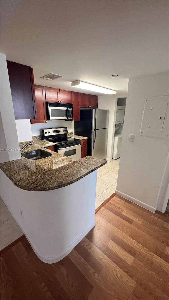 kitchen with electric panel, a sink, light wood-type flooring, dark brown cabinets, and stainless steel appliances