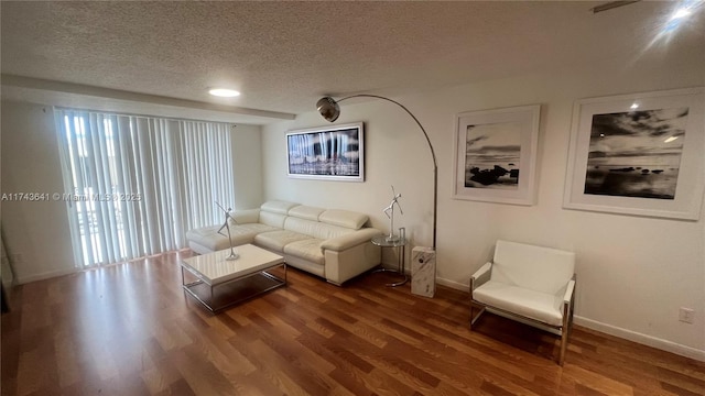 living area with baseboards, wood finished floors, and a textured ceiling
