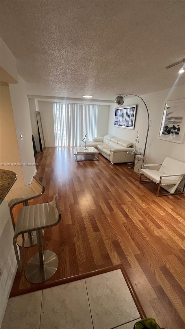 unfurnished living room with a textured ceiling and wood finished floors