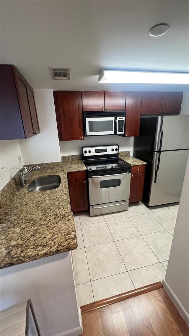 kitchen featuring dark stone countertops, light tile patterned floors, visible vents, appliances with stainless steel finishes, and a sink