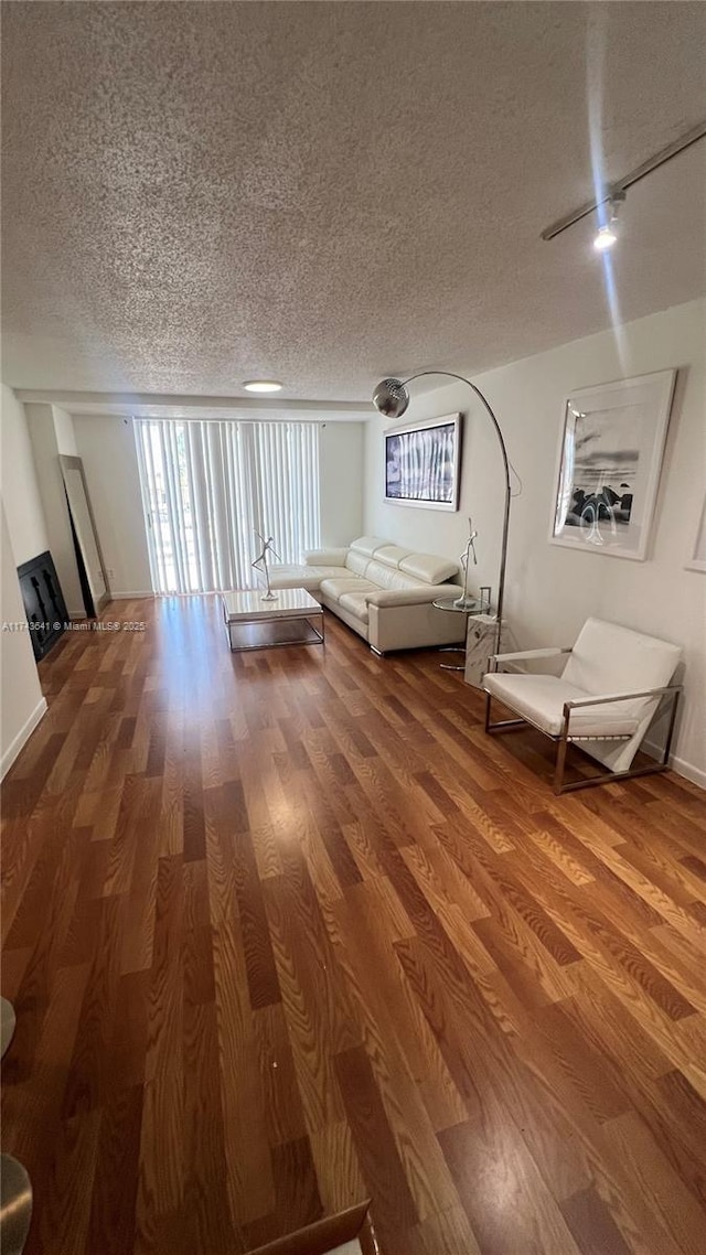 unfurnished living room featuring a wealth of natural light, a textured ceiling, and wood finished floors