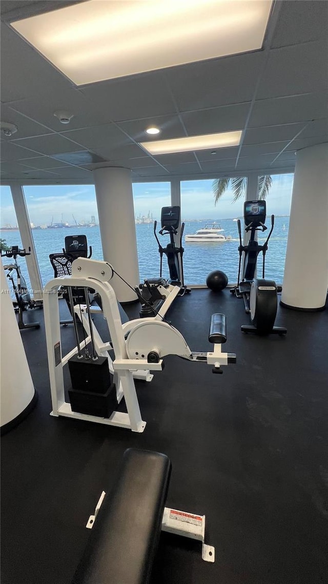 workout area featuring a water view, plenty of natural light, and a paneled ceiling