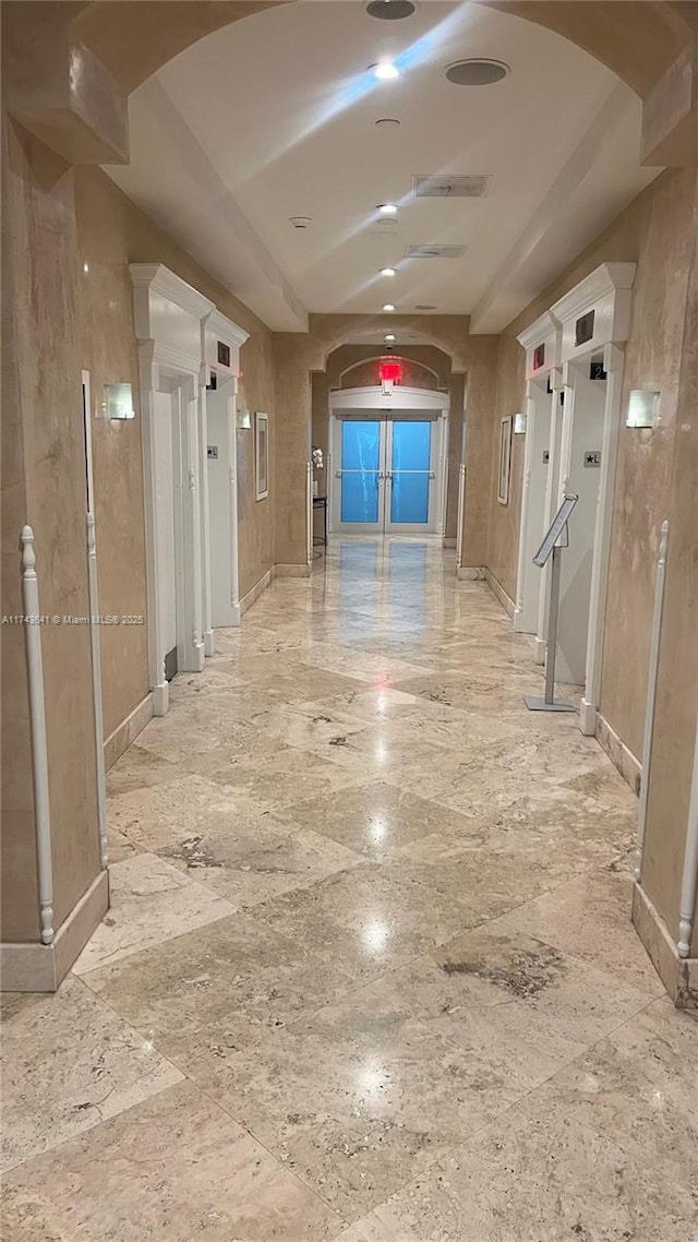 hall with baseboards and arched walkways