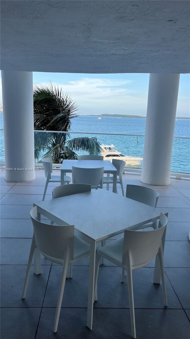 view of patio / terrace with outdoor dining area, a water view, and a balcony