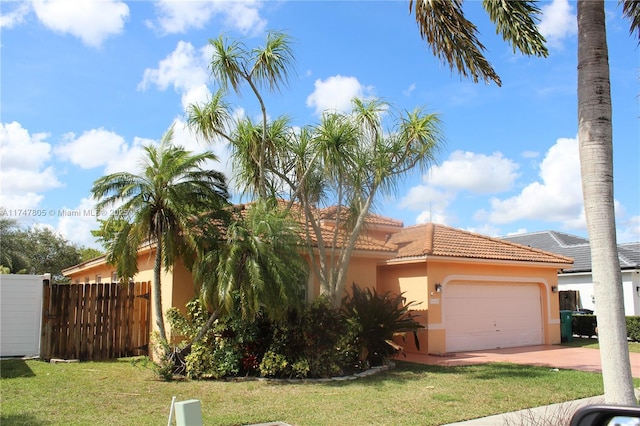 view of front of house with stucco siding, a tile roof, an attached garage, fence, and a front yard