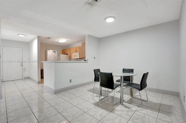 dining area with light tile patterned floors and a textured ceiling