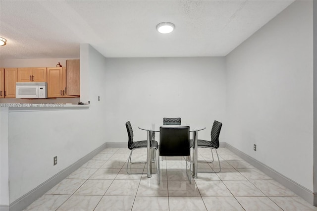 tiled dining room featuring a textured ceiling