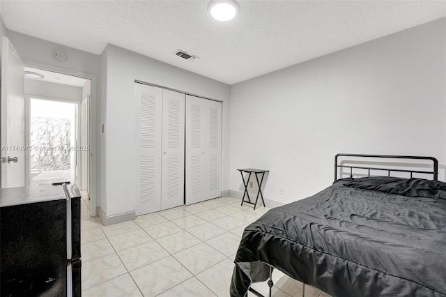 bedroom featuring light tile patterned flooring, a closet, and a textured ceiling