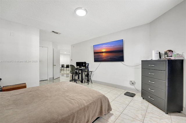 bedroom with a textured ceiling and light tile patterned floors