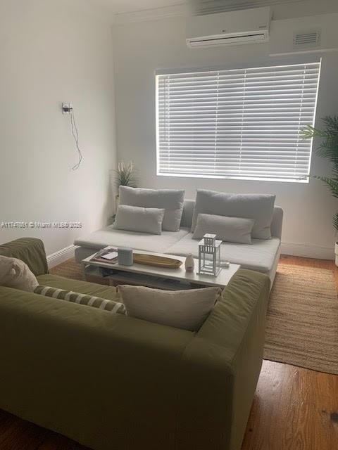 living room with a wall mounted AC, crown molding, and wood-type flooring