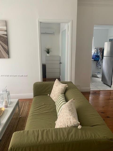 living room with hardwood / wood-style flooring, a wall unit AC, and crown molding