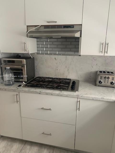 830 10th St Unit 1, Miami Beach, FL 33139 - kitchen featuring white cabinetry, stainless steel gas cooktop, backsplash, and light stone counters