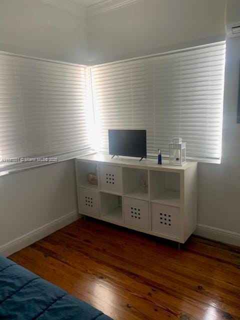 unfurnished bedroom with ornamental molding, dark hardwood / wood-style floors, and a wall mounted air conditioner