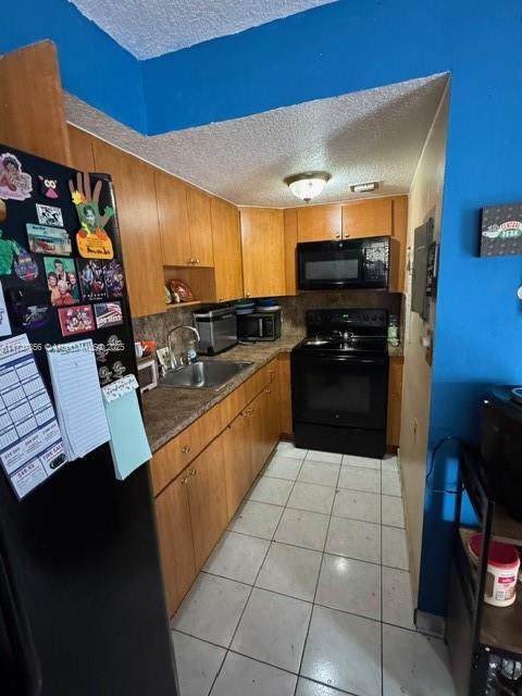 kitchen with black appliances, sink, backsplash, light tile patterned floors, and a textured ceiling