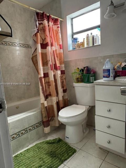 bathroom with shower / bath combo with shower curtain, tile walls, tile patterned flooring, and toilet