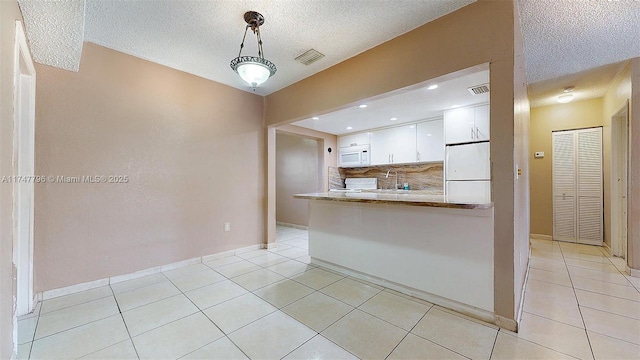 kitchen featuring kitchen peninsula, decorative light fixtures, white appliances, light tile patterned floors, and white cabinets