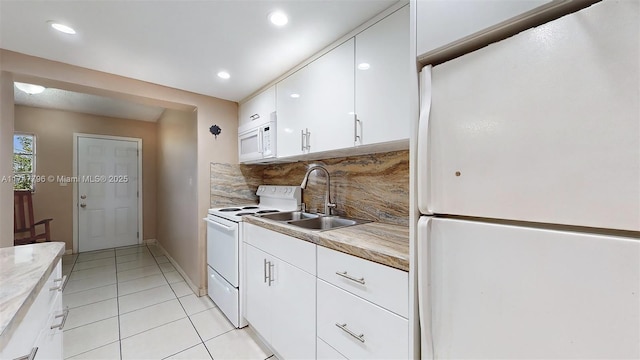 kitchen featuring tasteful backsplash, white appliances, white cabinets, light tile patterned floors, and sink