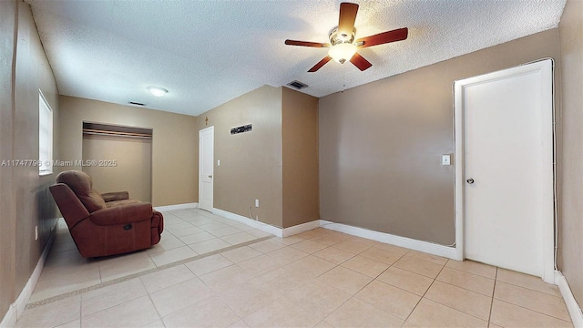 unfurnished room with a textured ceiling, ceiling fan, and light tile patterned floors