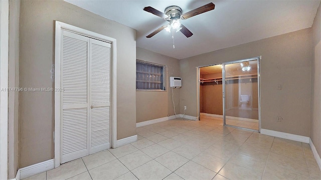 unfurnished bedroom with a closet, ceiling fan, a wall mounted AC, and light tile patterned floors