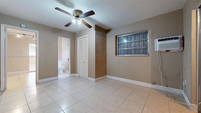 unfurnished bedroom featuring ceiling fan, light tile patterned floors, a closet, and a wall mounted air conditioner