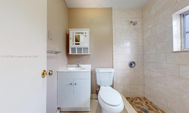 bathroom featuring toilet, vanity, and a tile shower