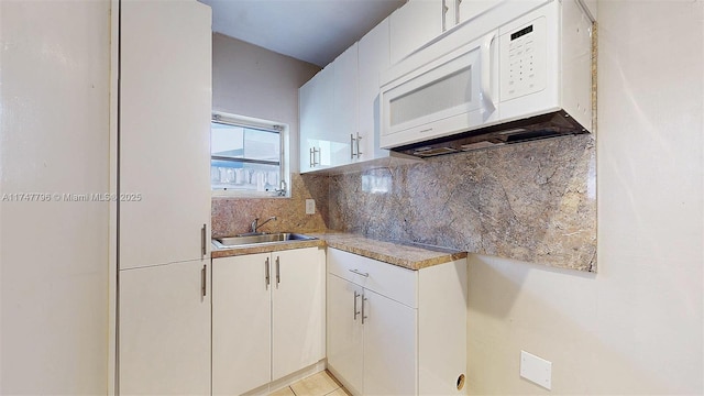 kitchen with white cabinetry, sink, backsplash, and light tile patterned floors