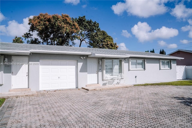 ranch-style home featuring a garage, decorative driveway, and stucco siding