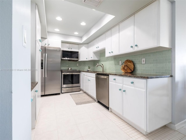 kitchen featuring stainless steel appliances, visible vents, white cabinets, decorative backsplash, and dark stone counters