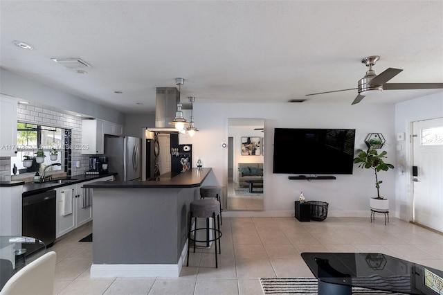 kitchen with black dishwasher, dark countertops, a sink, and freestanding refrigerator