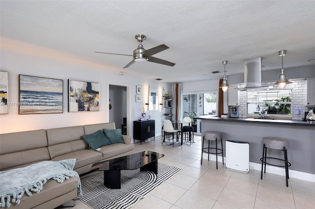 tiled living room with ceiling fan, sink, and a textured ceiling