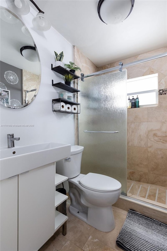 bathroom with vanity, a tile shower, toilet, and tile patterned floors