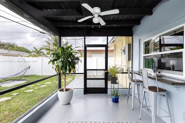 sunroom featuring beamed ceiling, ceiling fan, and wood ceiling