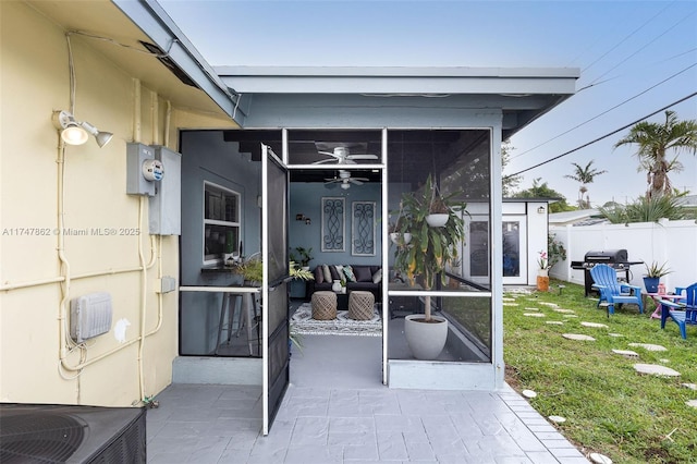 entrance to property with a patio, a yard, ceiling fan, and central AC