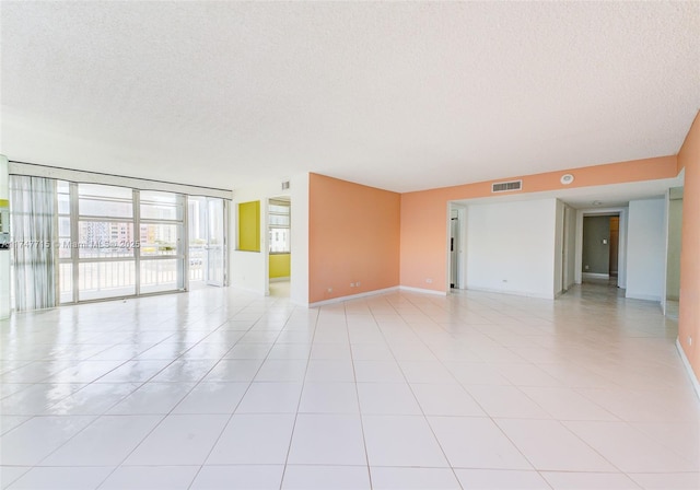 unfurnished room with a textured ceiling and light tile patterned floors