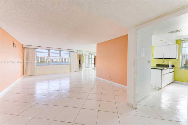 empty room featuring a textured ceiling and light tile patterned floors