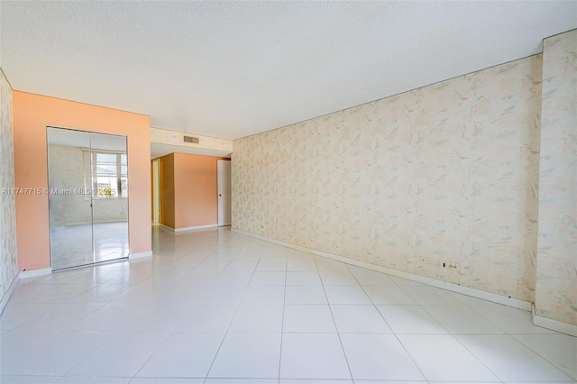 tiled empty room featuring a textured ceiling