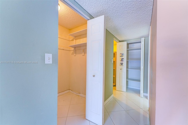 hallway featuring light tile patterned flooring and a textured ceiling