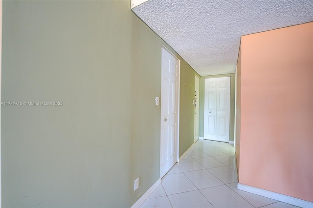 corridor featuring light tile patterned flooring and a textured ceiling