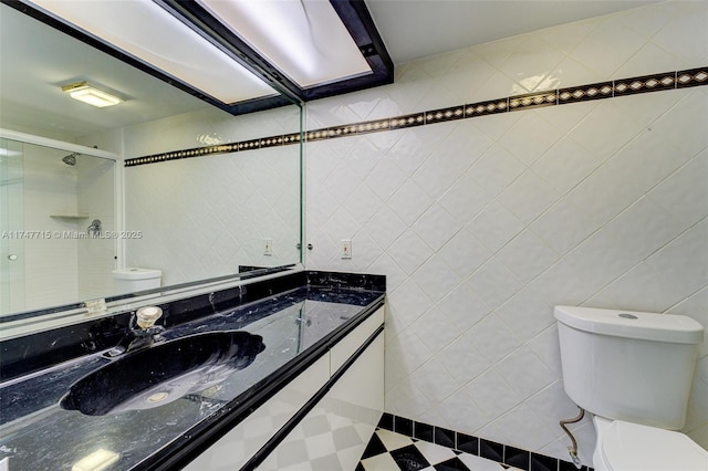 bathroom featuring toilet, tile walls, vanity, and walk in shower