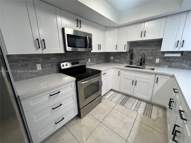 kitchen with decorative backsplash, sink, stainless steel appliances, and white cabinetry