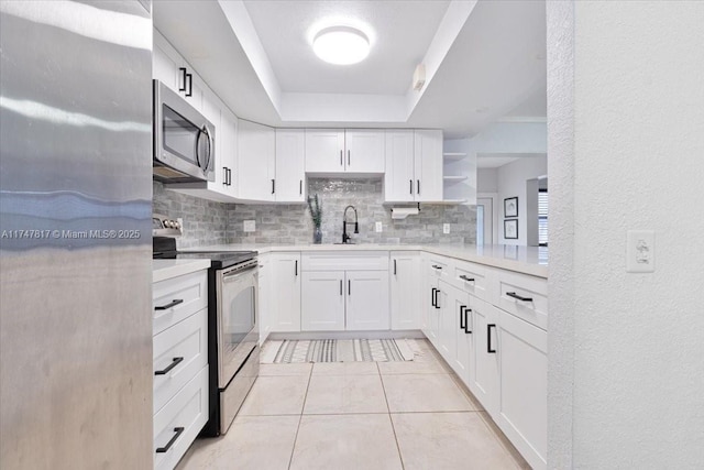 kitchen with open shelves, light countertops, decorative backsplash, appliances with stainless steel finishes, and white cabinetry